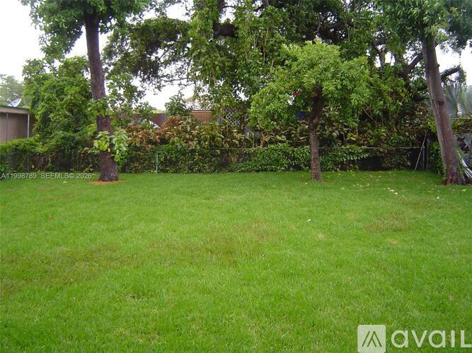 A backyard with a green lawn and trees.