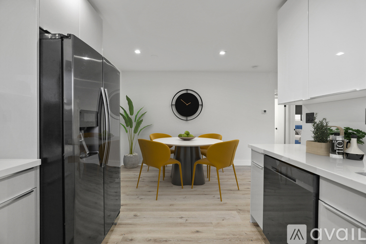 A modern kitchen with a black refrigerator and a round clock on the wall.
