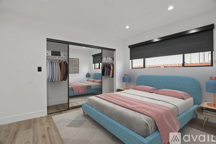 A bedroom with a blue bed and a mirrored closet.