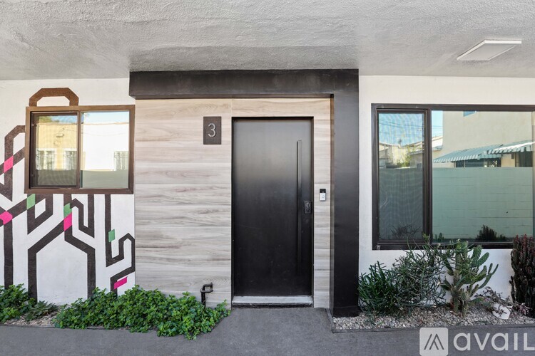 A modern house with a black door and a window with a view of a building in the background.