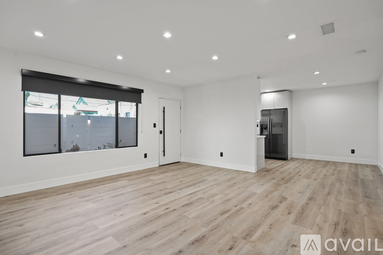 A spacious room with wooden flooring and a large window.