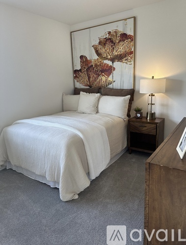 A bedroom with a large bed and a painting on the wall.