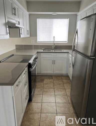 A kitchen with white cabinets and a stainless steel refrigerator.