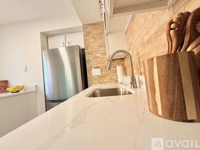 A kitchen with a stainless steel refrigerator and a wooden spice rack.