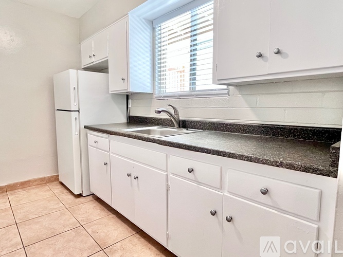 A kitchen with white cabinets and a black countertop.