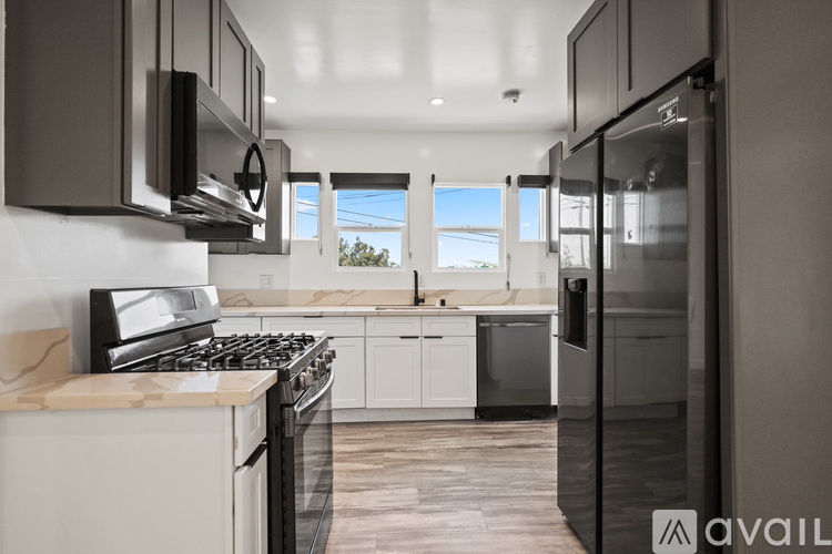 A modern kitchen with a stainless steel refrigerator and a gas range.