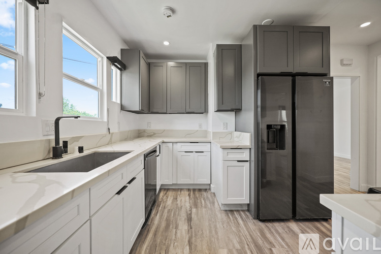 A modern kitchen with white cabinets and a black refrigerator.