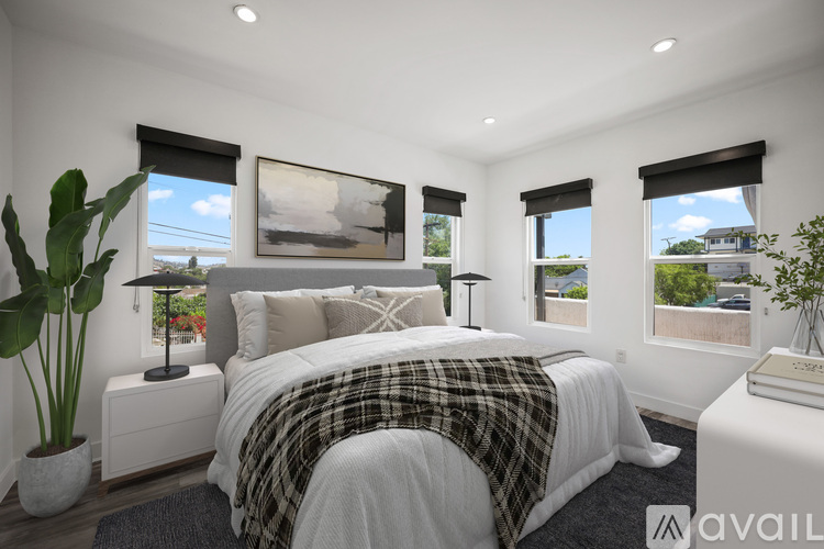 A bedroom with a large bed and a view of the outside through the windows.