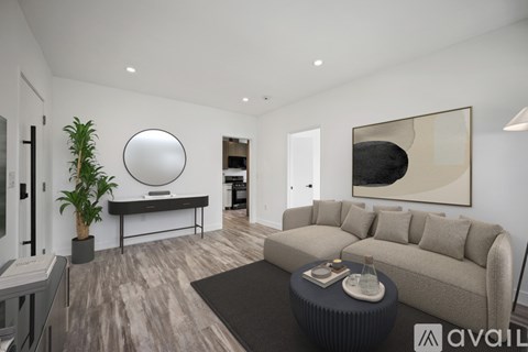 A modern living room with a large sofa, a round mirror, and a painting on the wall.