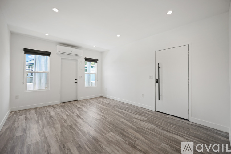 A spacious room with wooden flooring and two doors.