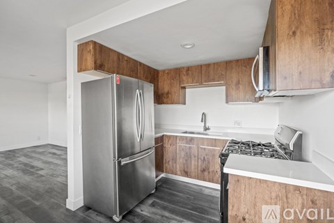 A kitchen with a stainless steel refrigerator and wooden cabinets.