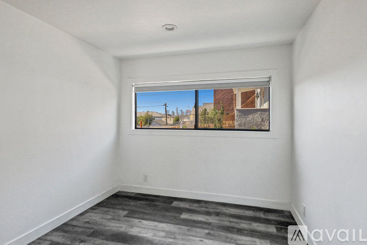 A room with a window showing a view of a building and trees outside.