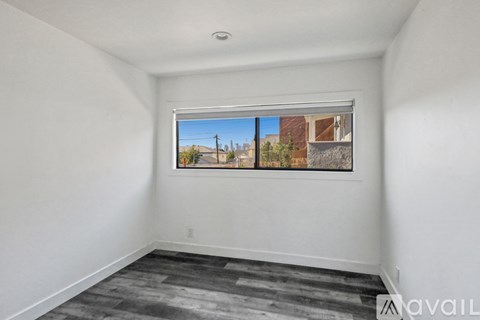 A room with a window showing a view of a building and trees outside.