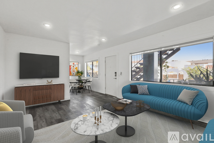 A living room with a blue couch and a television on the wall.