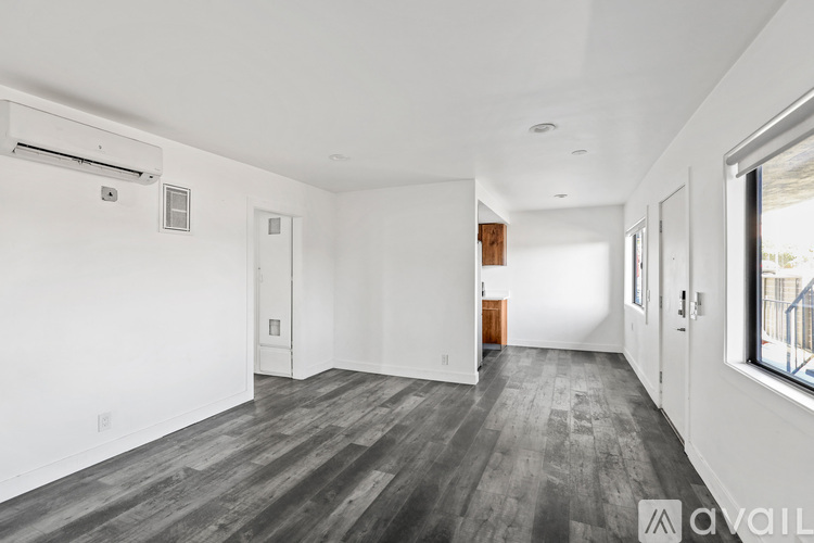 A spacious room with wooden flooring and white walls.