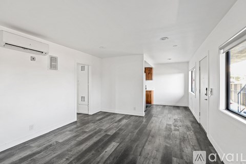A spacious room with wooden flooring and white walls.