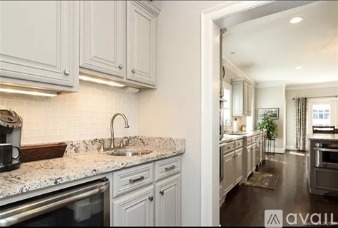 A kitchen with white cabinets and a marble countertop.