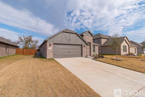 A large house with a garage is surrounded by a fence and has a driveway leading to it.
