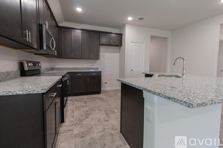 A kitchen with granite countertops and black cabinets.