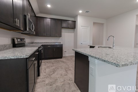 A kitchen with granite countertops and black cabinets.