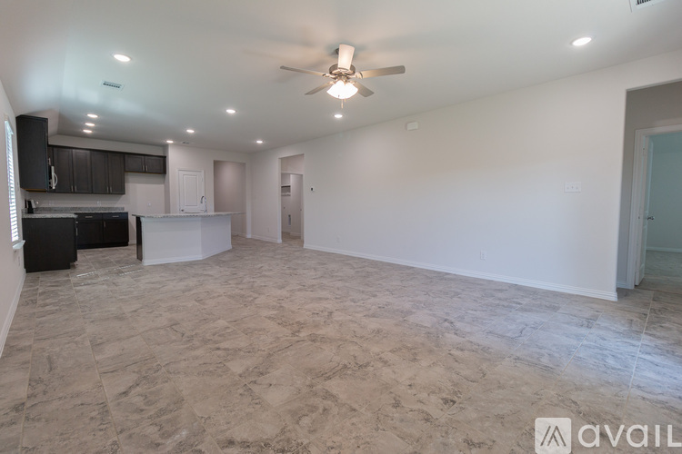 A spacious empty room with a ceiling fan and tiled flooring.