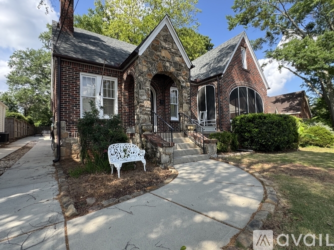 A white bench sits in front of a brick house.