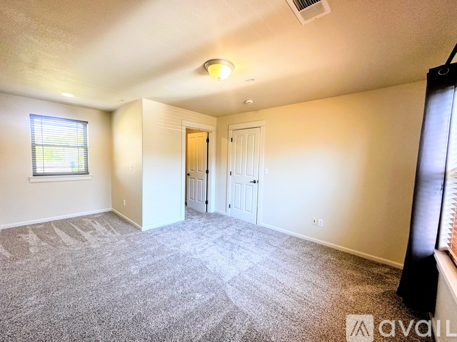 A spacious room with a carpeted floor and a window with blinds.