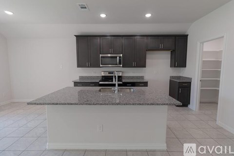 A kitchen with granite countertops and dark cabinets.