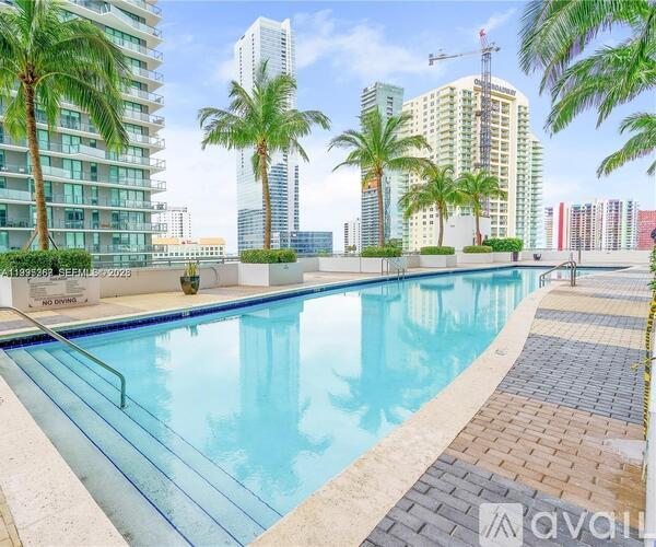 A large swimming pool surrounded by palm trees and modern buildings.