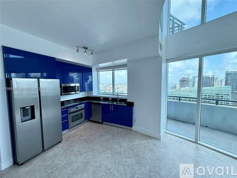 A modern kitchen with blue cabinets and a stainless steel refrigerator.