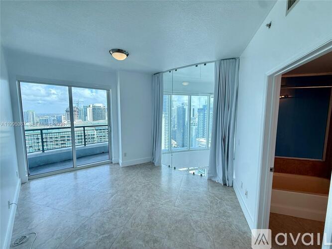 A spacious living room with a view of the cityscape outside the large windows.