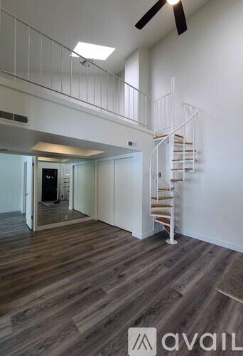A room with a spiral staircase and wooden flooring.
