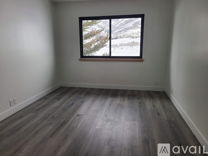 A room with a large window showing a snowy landscape outside.
