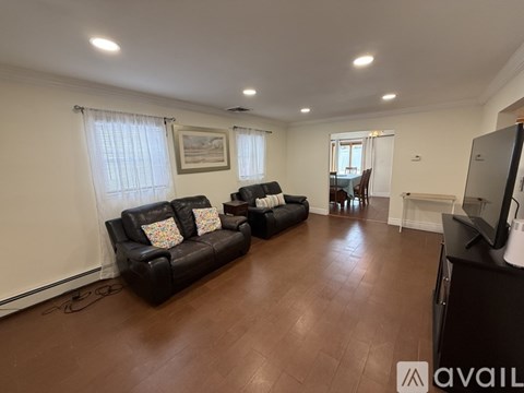 A living room with black leather couches and a television.