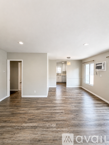 A spacious room with wooden flooring and white walls.
