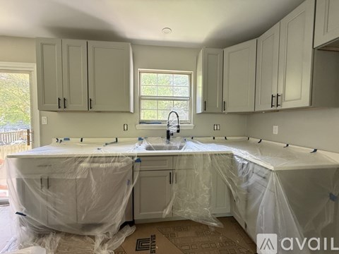 A kitchen under renovation with cabinets and a sink covered in plastic.
