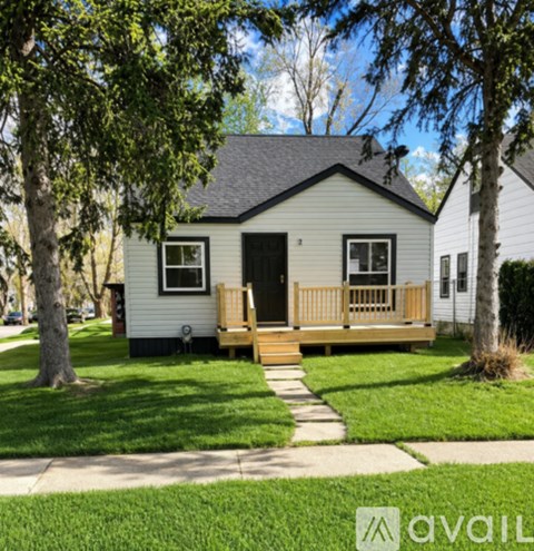 A small house with a porch and a tree in front.