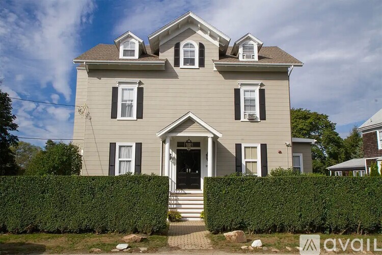 A two-story house with a grey facade and a black door.