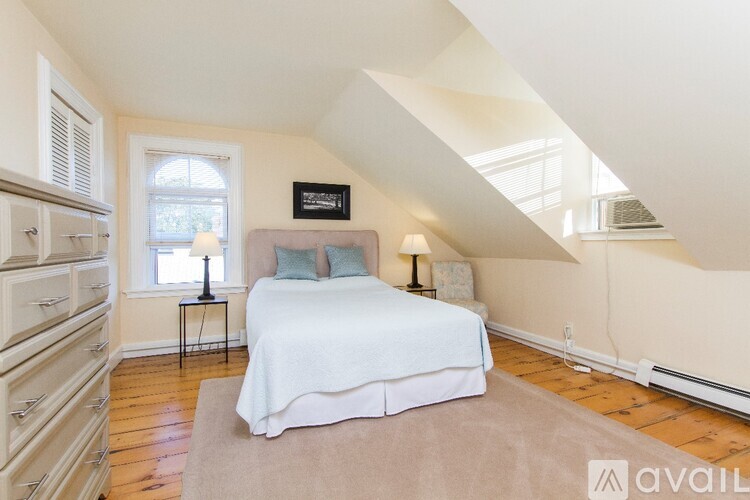A bedroom with a bed, a window, and a nightstand.