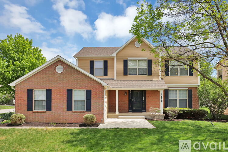 A two-story house with a brick facade and a large front yard.