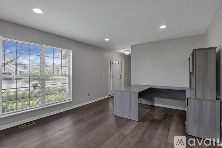 A spacious room with a large window and a wooden floor.