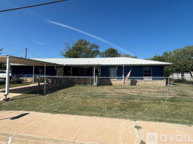 A blue building with a white roof and a fence in front of it.