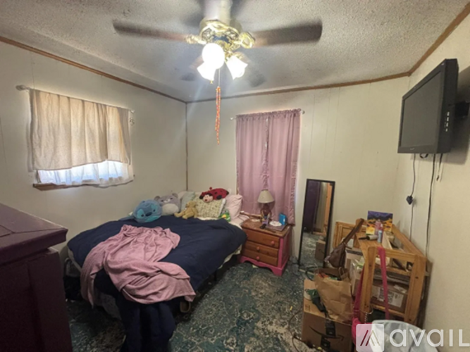 A bedroom with a bed, dresser, and ceiling fan.