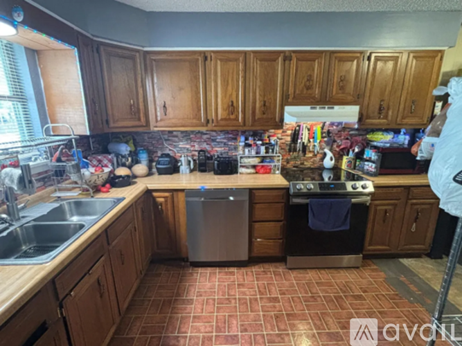 A kitchen with wooden cabinets and a red tile floor.