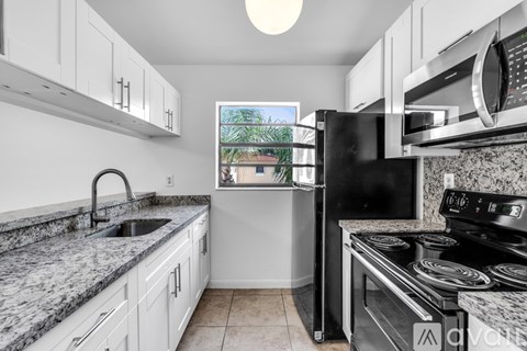 A kitchen with granite countertops and white cabinets.