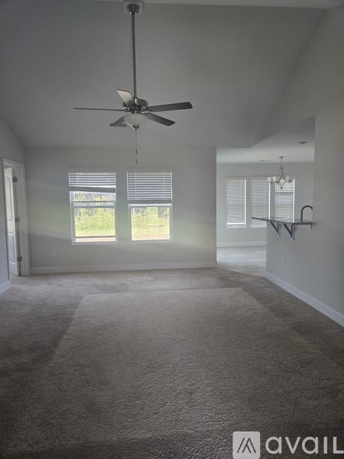 A room with a ceiling fan and carpeted floor.