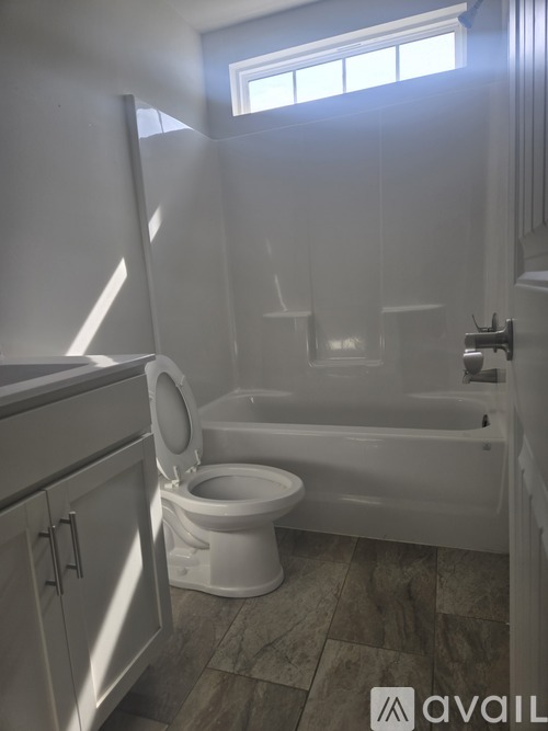 A white toilet is in a bathroom with a tub and sink.