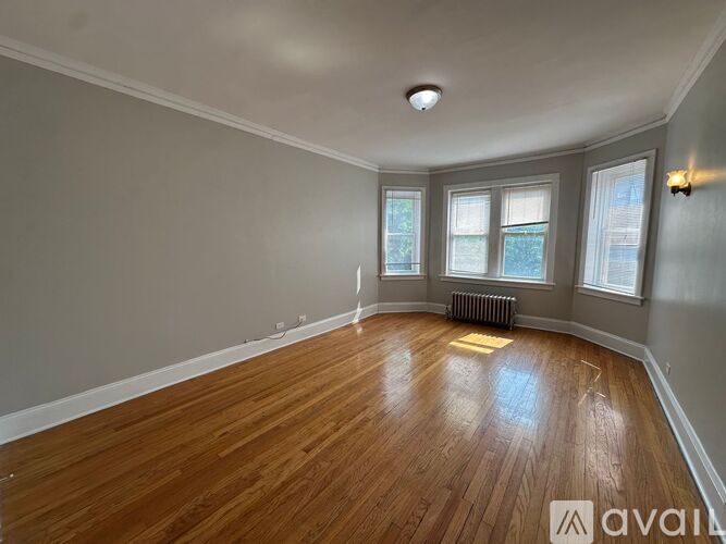 A room with wooden flooring and a window with a view of trees.