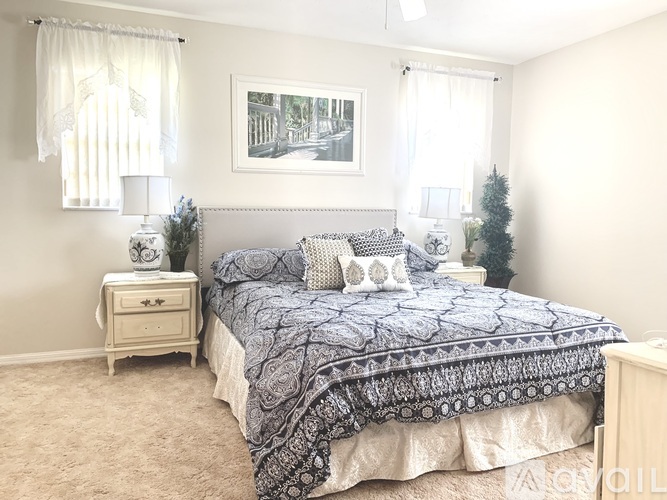 A bedroom with a large bed and a nightstand with a lamp.