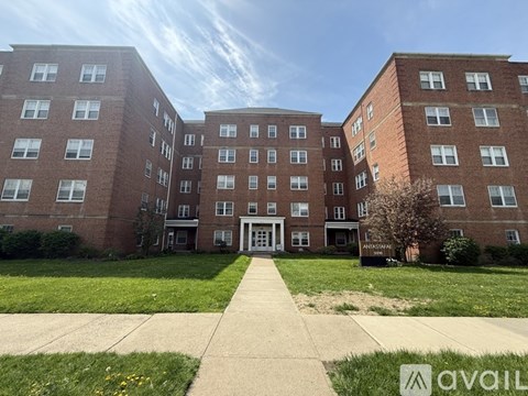 A large brick building with a walkway in front and a sign that says "AVAILABLE".